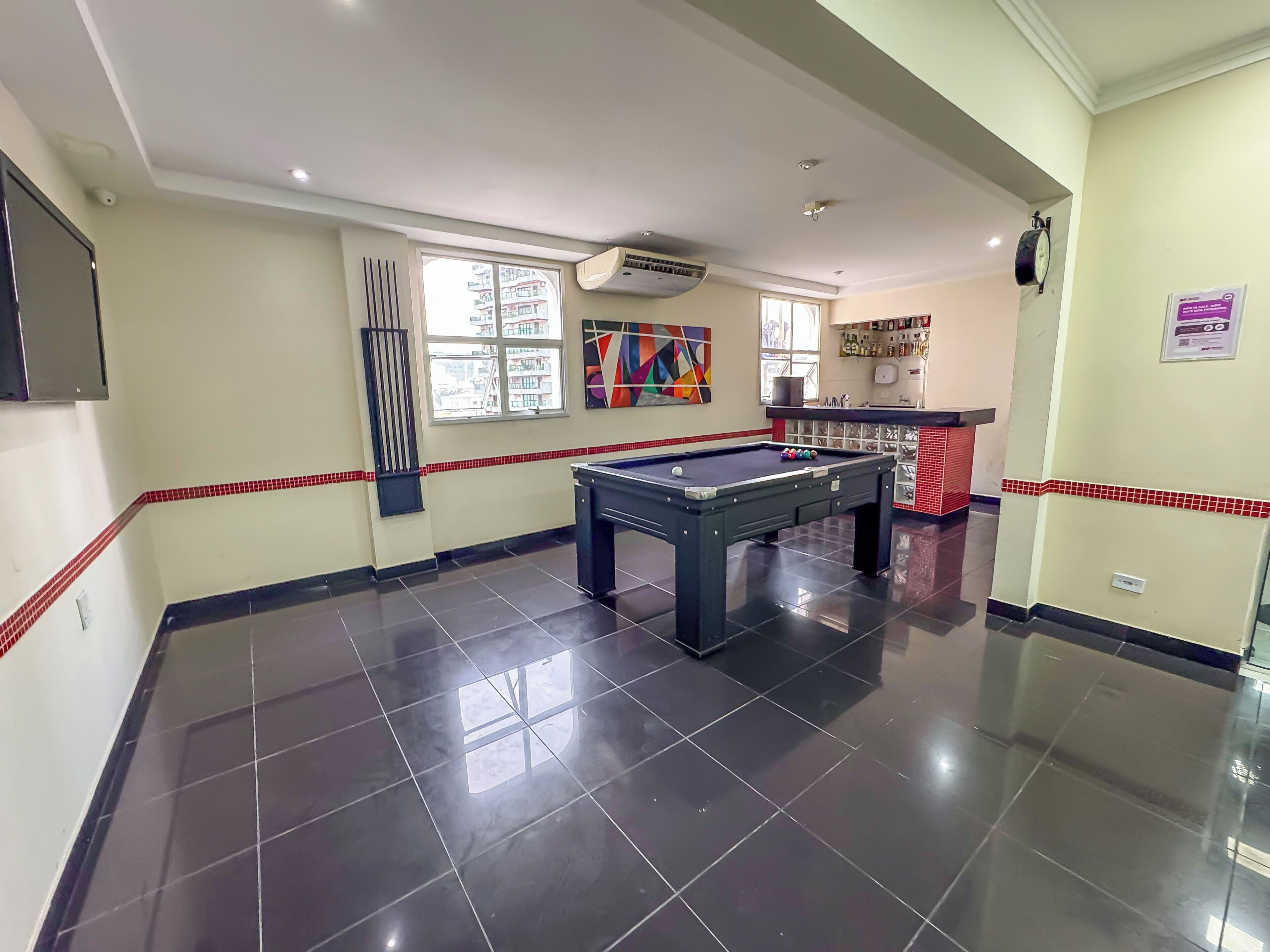 A billiards room with a pool table, a window with blinds, and a wall-mounted air conditioner.