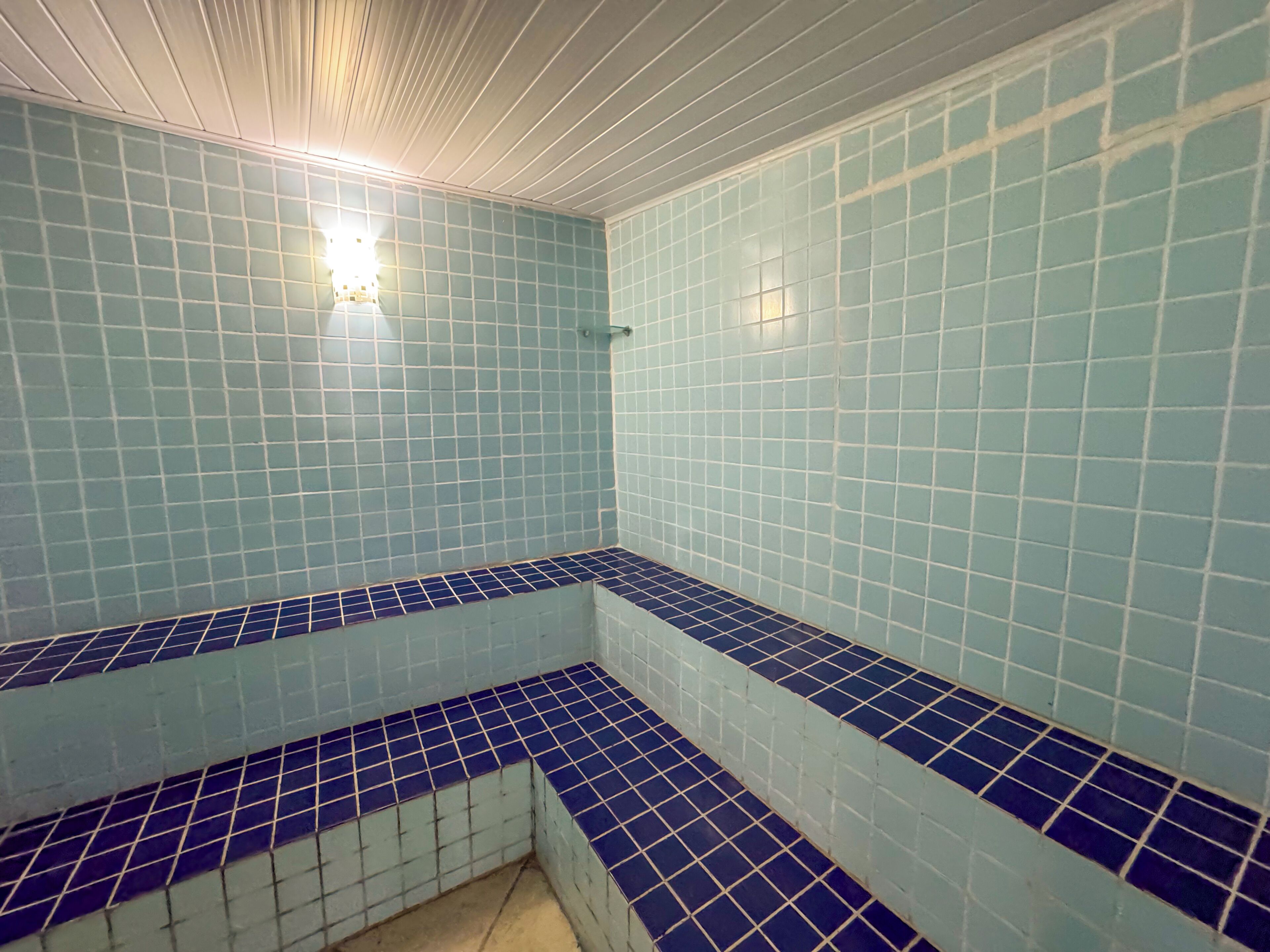 A room with blue-tiled walls and a corner bench.
