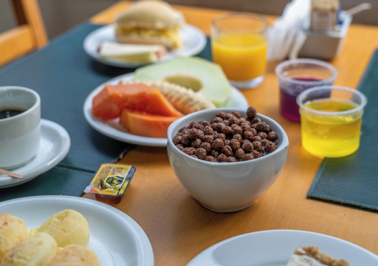Una mesa de desayuno con platos de comida, un tazón de cereal y una taza de café.