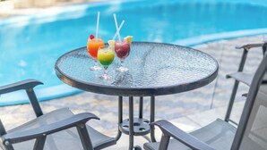 A round table with three drinks and a pool in the background. - Hotel Nacional Inn Guarujá (Guarujá)