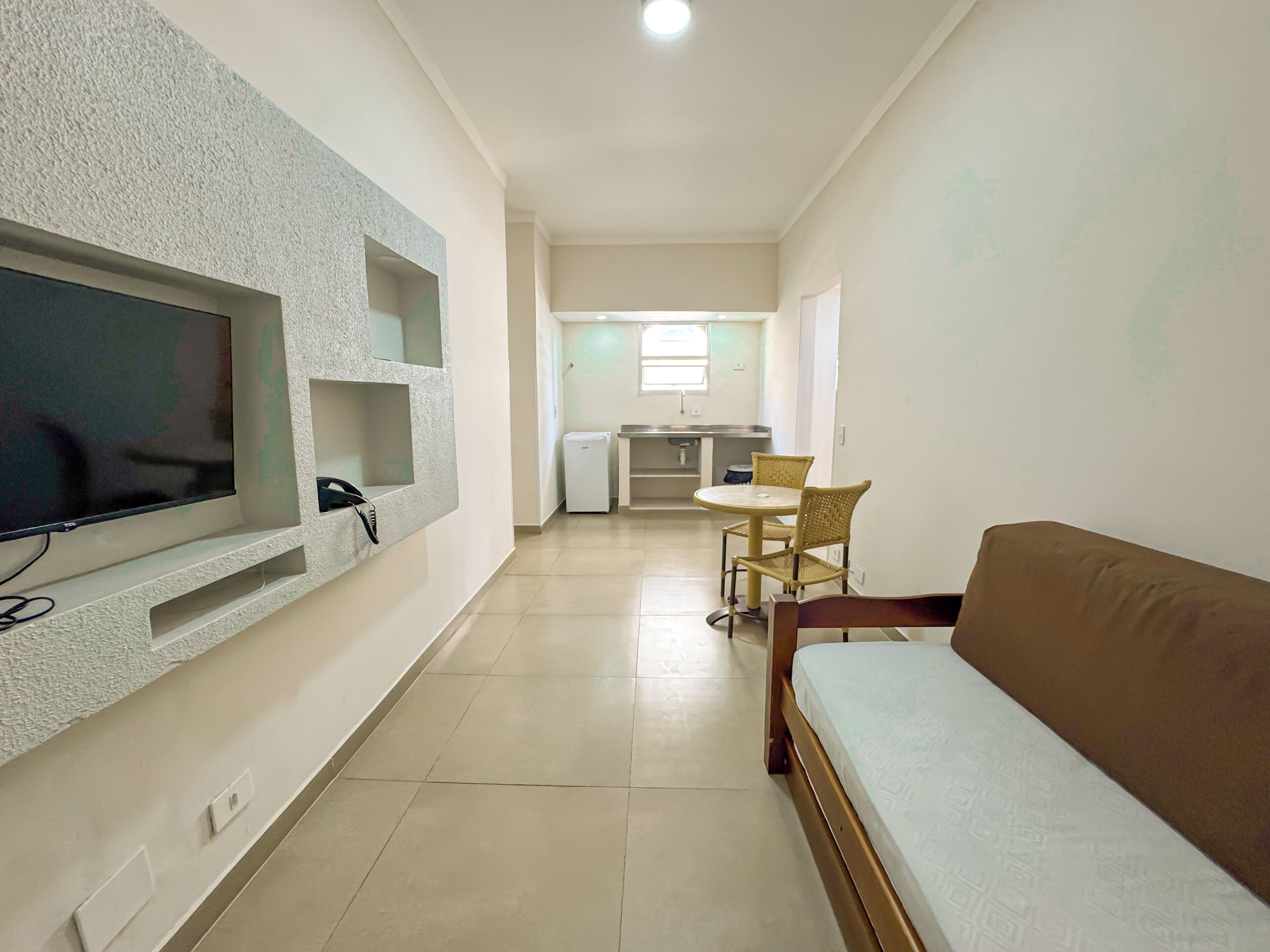Een moderne woonkamer met een flatscreen televisie, een bank en een eethoek met een tafel en stoelen.
