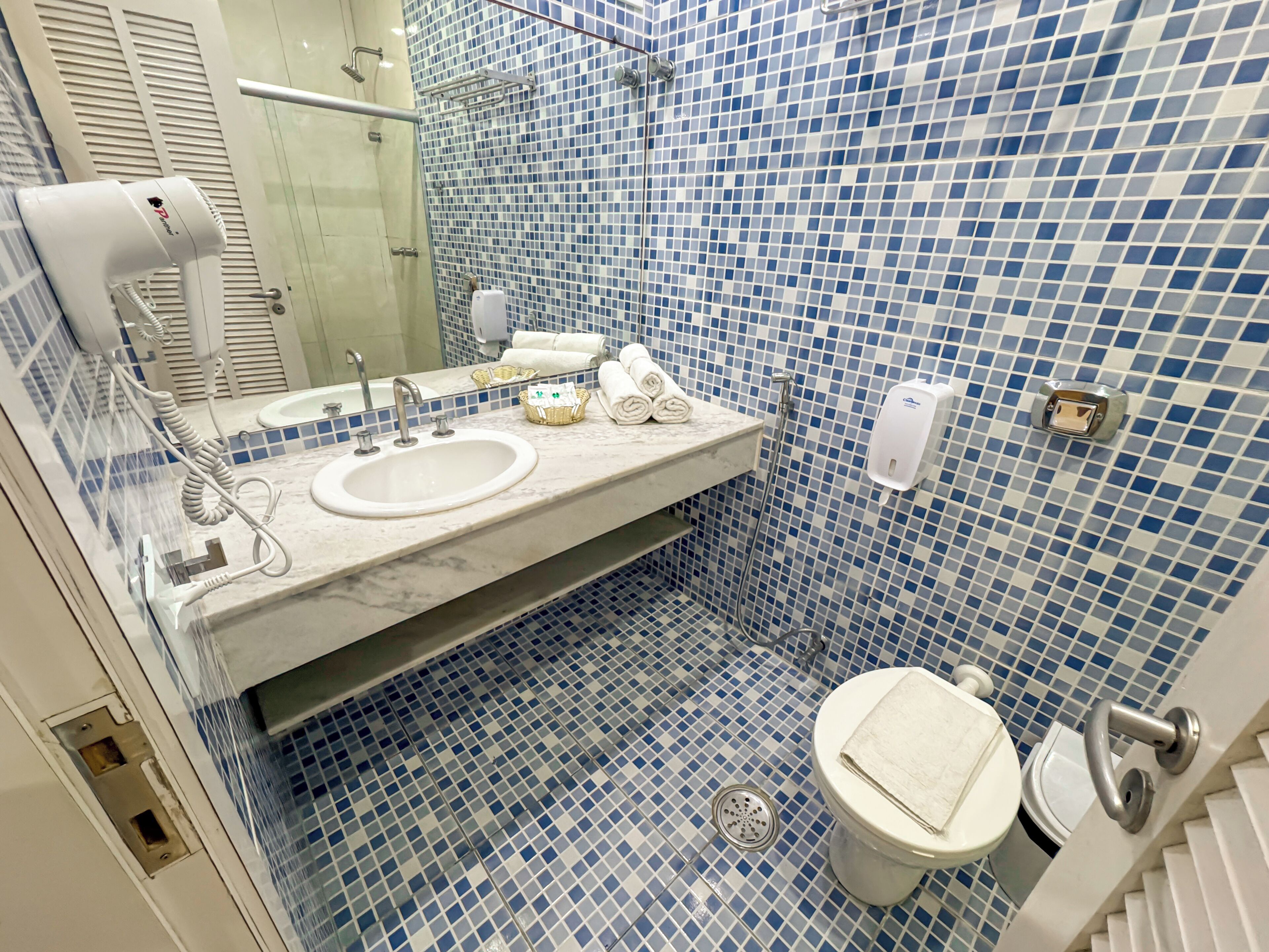 Un baño con lavamanos, espejo e inodoro.