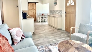 A spacious living area with a sofa, a coffee table, and a dining table in the background. - Home Sweet Home (Sanford)