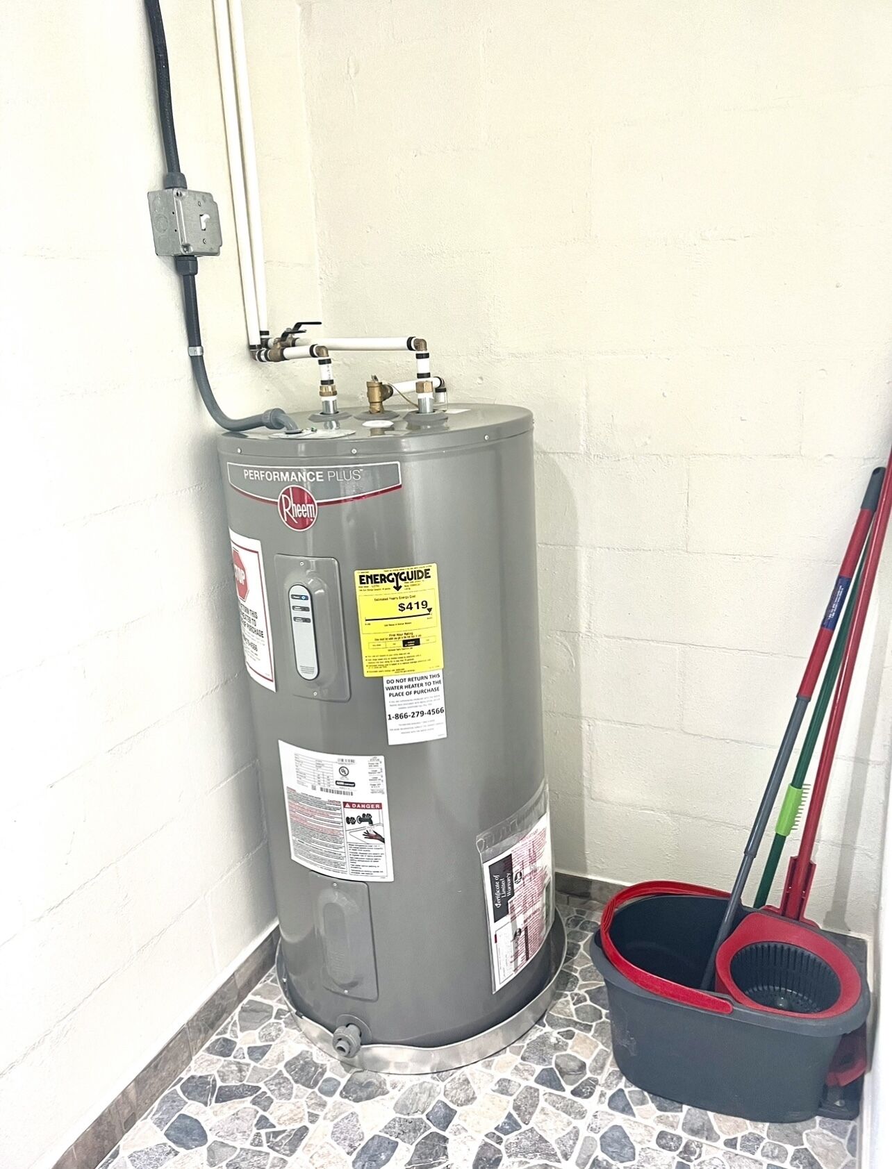 A water heater with a label indicating a price of $419, a warning not to return water to the place of purchase, and a contact number.