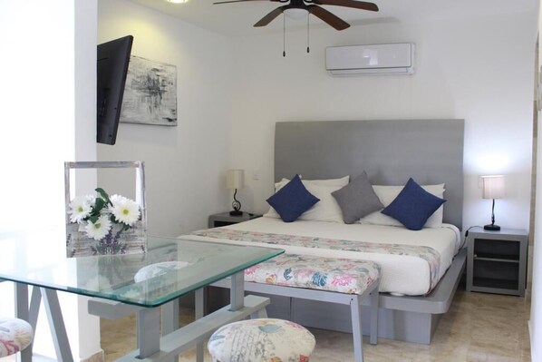 A bedroom with a bed, bedside tables, a desk, and a ceiling fan.