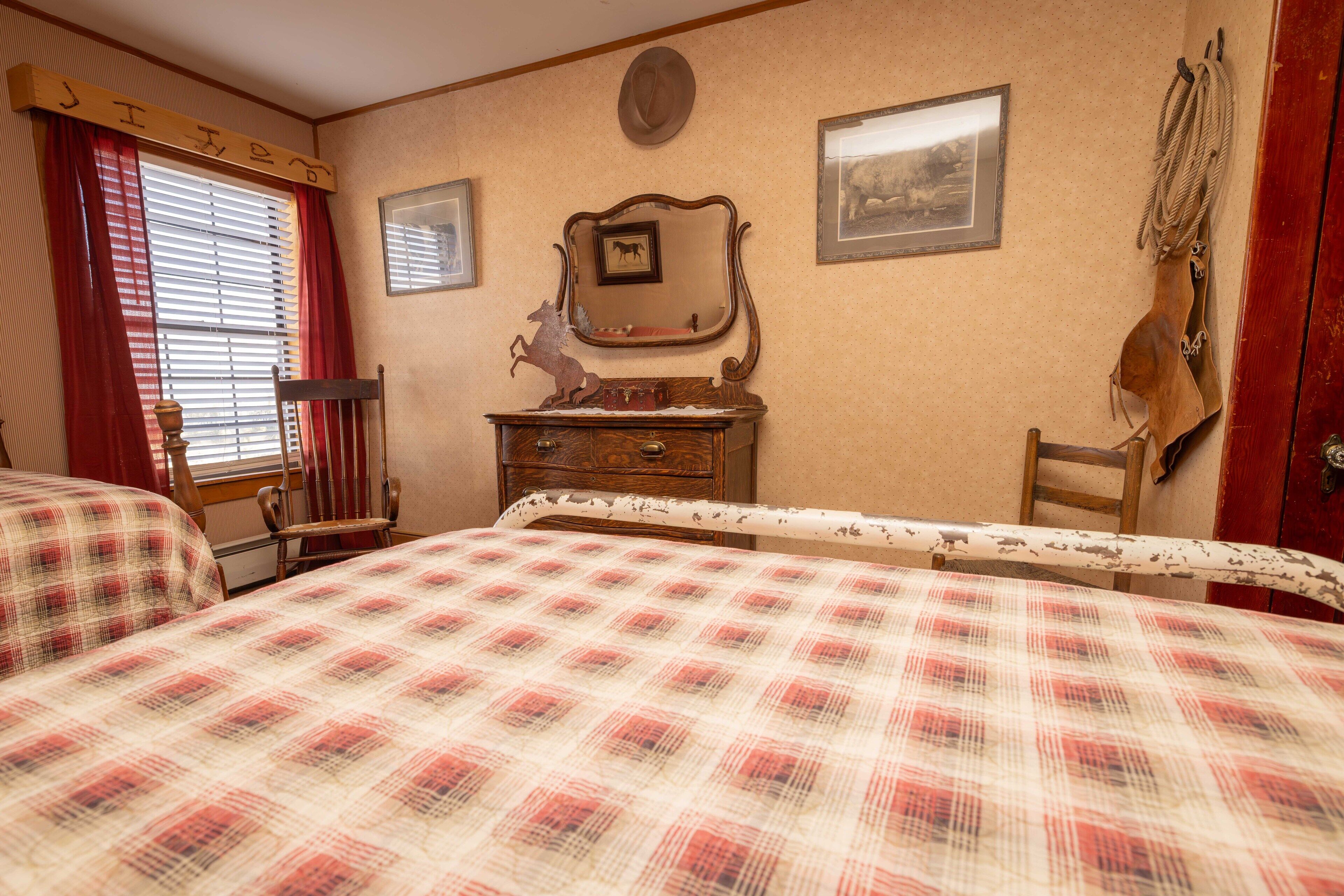 A bedroom with two beds, a dresser, a chair, a mirror, and a coat rack.