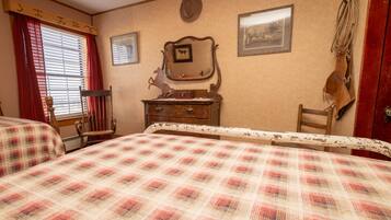 A bedroom with two beds, a dresser, a chair, a mirror, and a coat rack.