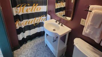 A bathroom with a striped shower curtain, a sink, a mirror, and a toilet.