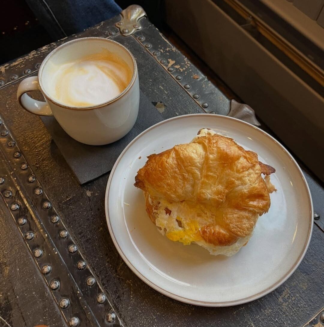 A plate with a pastry and a cup of coffee on a table.