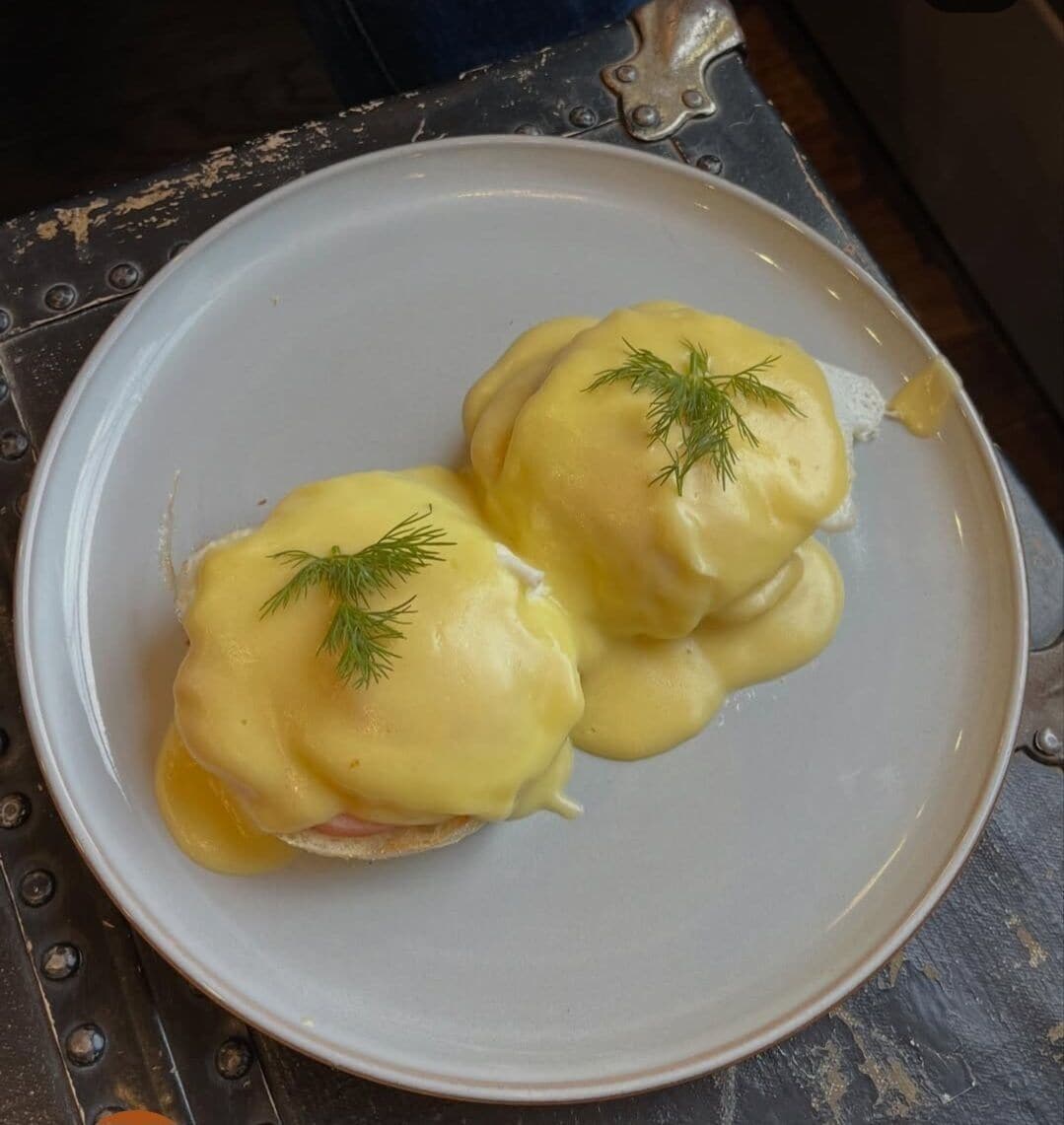 A plate with two eggs benedict garnished with dill.