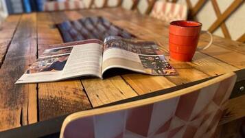 A wooden table with a magazine and a red cup.