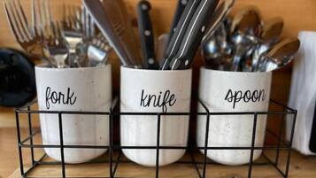 Three kitchen utensil holders labeled 'fork,' 'knife,' and 'spoon' on a wooden surface.