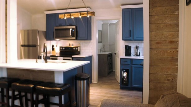 A modern kitchen with blue cabinets, a stainless steel refrigerator, a microwave, and a coffee maker. - Near Riverwalk, Hemisfair, Art & Dining Spots (San Antonio)