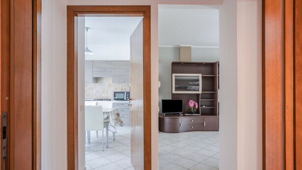 A modern kitchen with a microwave, stove, and dining area visible through an open door.