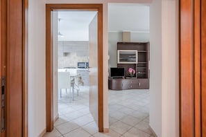 A modern kitchen with a microwave, stove, and dining area visible through an open door.