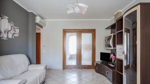 A living room with a sofa, a TV, a cabinet, and a door with frosted glass panels.