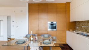 Une cuisine moderne avec des meubles en bois, une table à manger en verre et un four encastré.