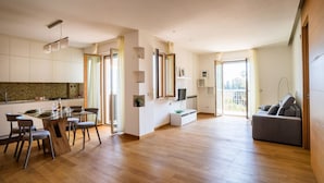 Un grand espace de vie comprenant une table à manger, des chaises, un canapé et une cuisine en arrière-plan.