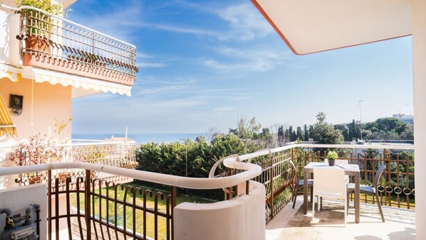 Un balcon avec vue sur la mer, une table avec des chaises et une rambarde.
