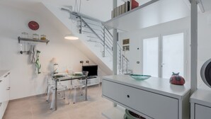 Une cuisine moderne avec un coin repas, un escalier et une vue sur l’extérieur.