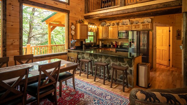A wooden cabin with a kitchen, dining area, and a balcony.