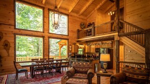A spacious wooden cabin with a dining area, a cozy living room with a fireplace, and a kitchen.
