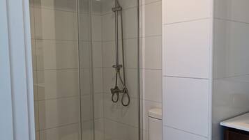A modern bathroom with a glass-enclosed shower, a white toilet, and a wooden floor.