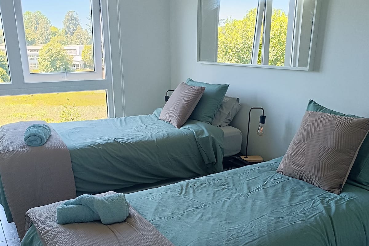 Een kamer met twee bedden, een raam en een nachtkastje.