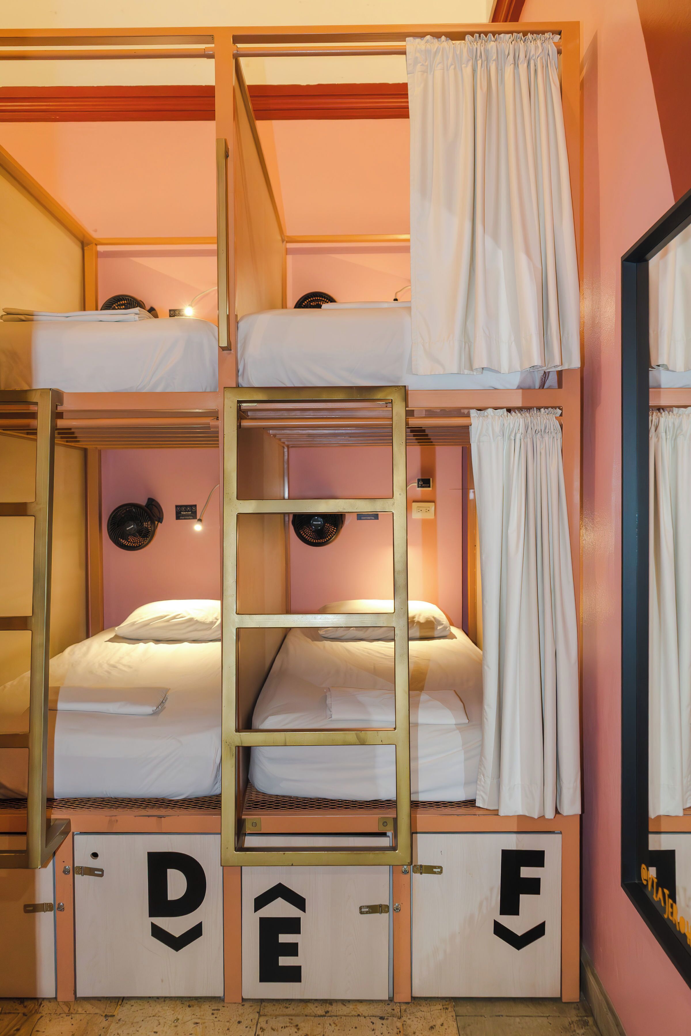 A bunk bed room with a ladder, a mirror, and a fan.
