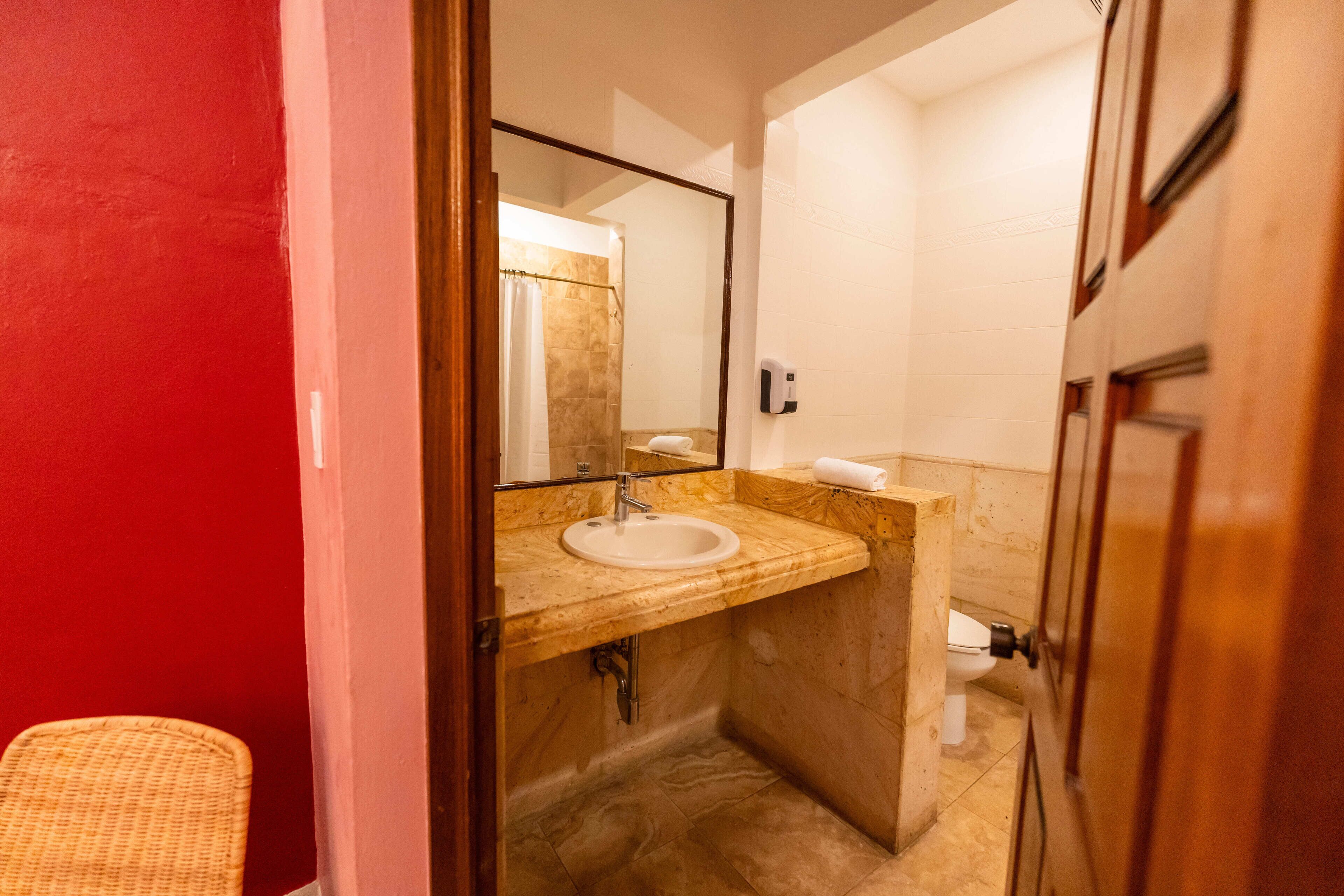 Une salle de bain avec un lavabo en marbre, un miroir et un espace douche.