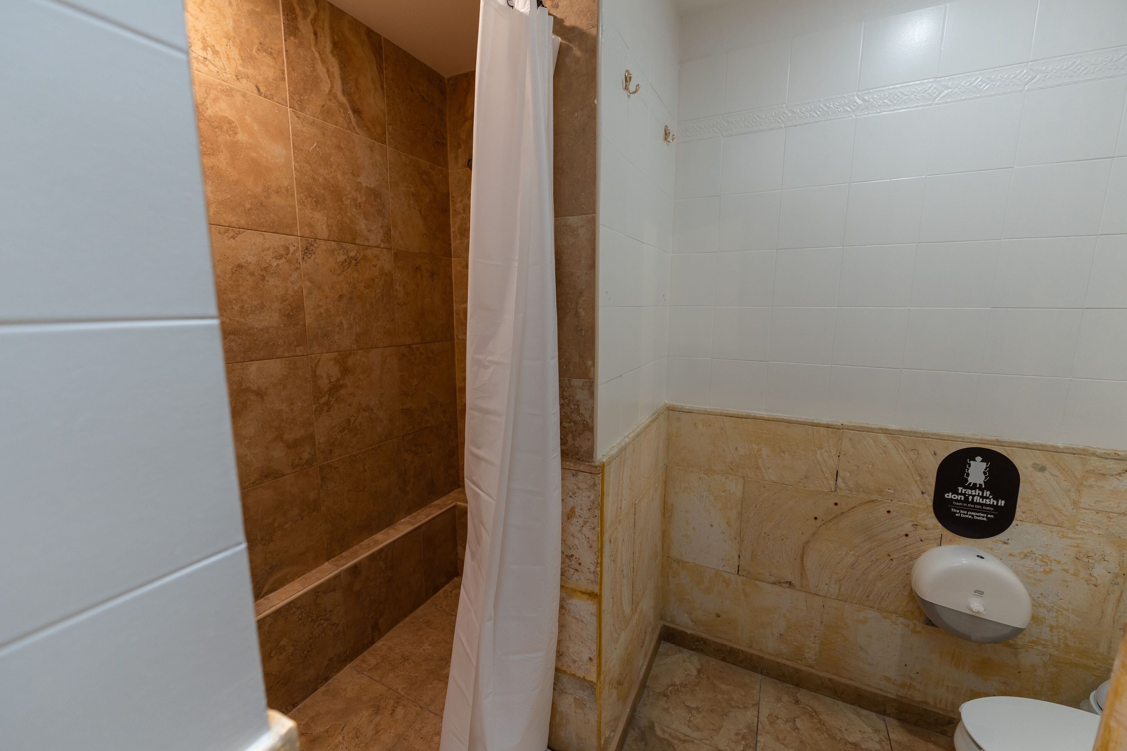 A bathroom with a shower, a toilet, and a hand dryer.