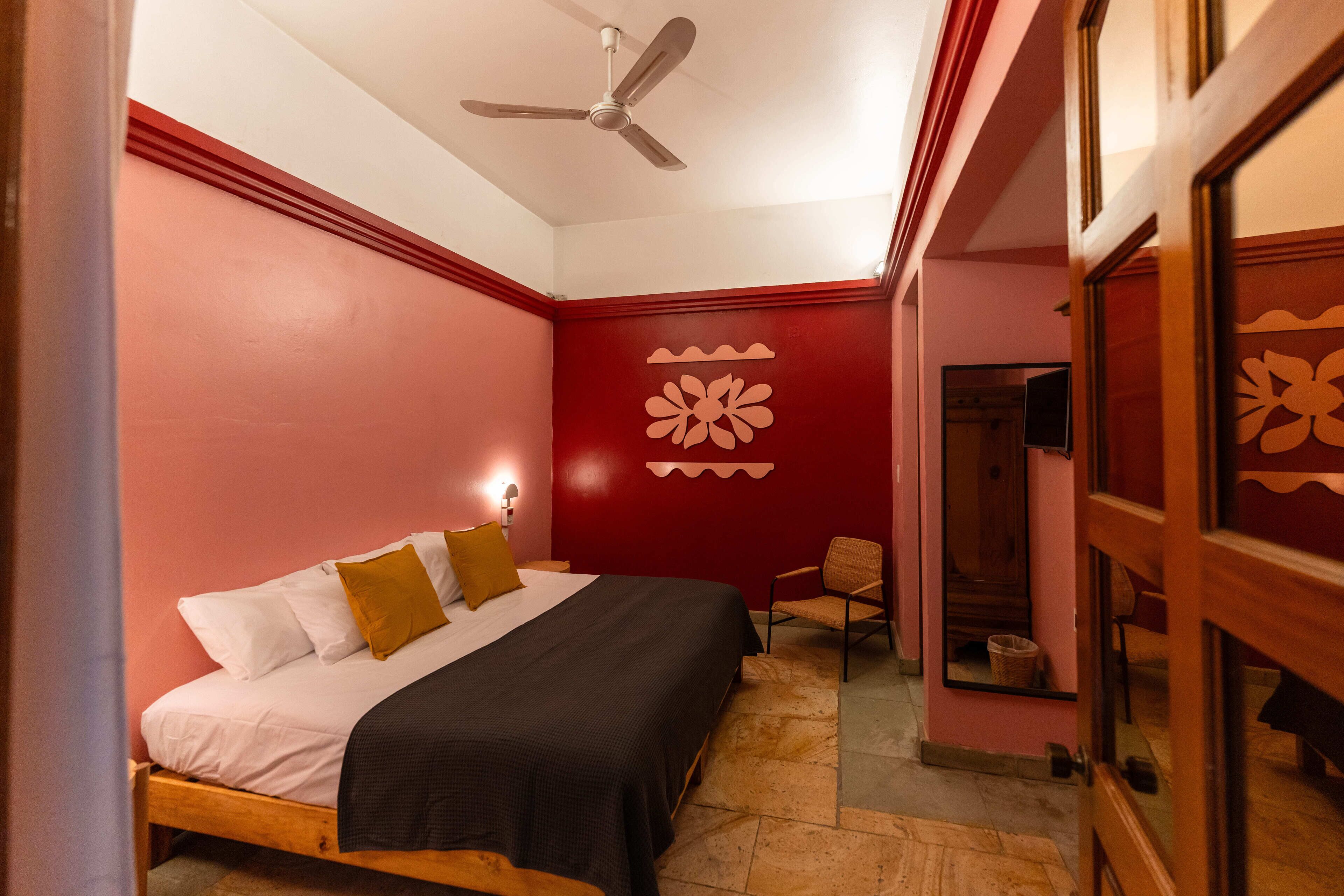 Un dormitorio con cama, ventilador de techo y una silla.