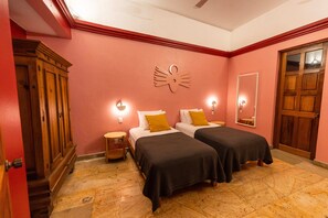 A room with two beds, a wooden wardrobe, a wall-mounted light fixture, and a mirror. - Viajero Oaxaca Hostel (Oaxaca)
