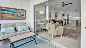 A modern living room with a sofa, coffee table, and a glass door leading to a kitchen area. - Coastal Cottage-Steps to Siesta Key Beach (Siesta Key)