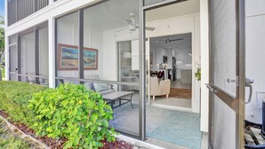 A modern house with a glass door leading to a living area with a sofa, a dining table, and a kitchen visible through the glass. - Coastal Cottage-Steps to Siesta Key Beach (Siesta Key)