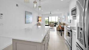 A modern kitchen with white cabinetry, stainless steel appliances, and pendant lighting. - Coastal Cottage-Steps to Siesta Key Beach (Siesta Key)