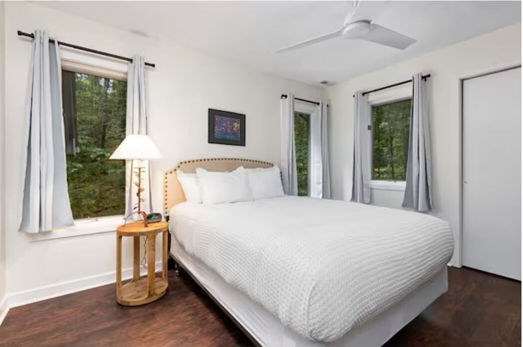 A bedroom with a bed, a bedside table, a lamp, and a ceiling fan.