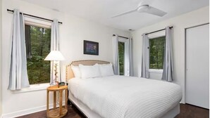 Une chambre à coucher avec un lit, une table de chevet, une lampe et un ventilateur de plafond.