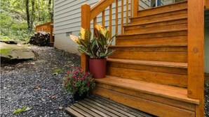 Un escalier en bois menant à une maison, avec un pot de fleurs placé sur les marches.