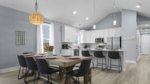 A modern kitchen with white cabinets, a wooden island, and black bar stools. - Two Amazing Modern & Spacious Beach Retreats, 9 Bedroom, 6 bathrooms (Gulfport)