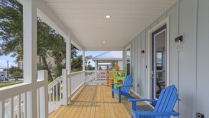 A covered porch with a wooden deck, white railings, and blue chairs. - Two Amazing Modern & Spacious Beach Retreats, 9 Bedroom, 6 bathrooms (Gulfport)