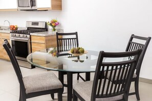 A modern kitchen with a round glass table, four chairs, and a stove. - New Townhouse, A/C, secure and great location! (Ensenada)