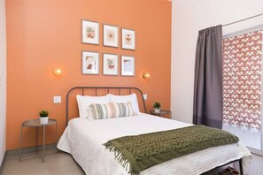 A bedroom with a bed, two bedside tables, a wall-mounted light, and a window with curtains. - New Townhouse, A/C, secure and great location! (Ensenada)