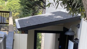 Un ingresso stretto con una porta in legno, un piccolo portico e un tappetino nero che conduce alla porta.