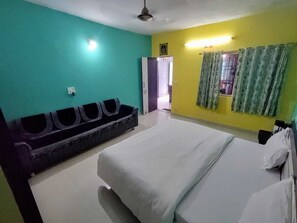 A room with a bed, a bench, and a door leading to another room. - Charan Villa (Abu Road)