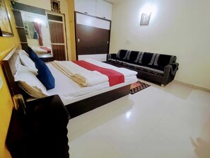 A hotel room with a bed, a sofa, a wardrobe, and a mirror. - Charan Villa (Abu Road)