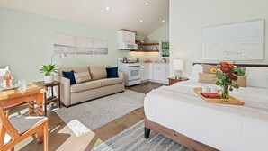 A modern hotel room with a bed, a dining table, a sofa, a kitchen area, and artwork on the walls. - Comfortable Montecito Studio Cottage Walking Distance to Beach! (Santa Barbara)