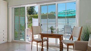A room with a dining table, chairs, and a sliding glass door leading to an outdoor patio with a table and chairs. - Comfortable Montecito Studio Cottage Walking Distance to Beach! (Santa Barbara)