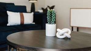 Taula de fusta rodona amb un vas blanc que conté un cactus i una corda blanca retorçada.