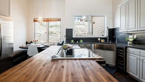 A modern kitchen with a central island, stainless steel appliances, and a view of the backyard. - Lower Deer Valley with Amazing Views, Private Hot Tub, Walk to Old Town (Park City)